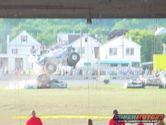 Monster truck airborne over crushed cars during an event