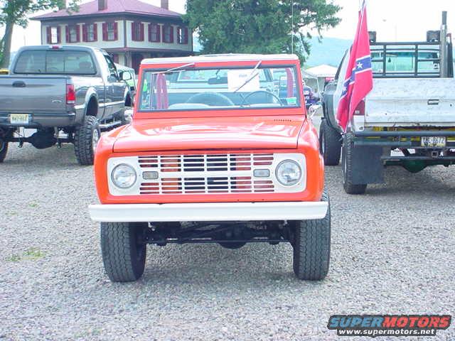 Orange SUV with a white grille and round headlights, parked on gravel
