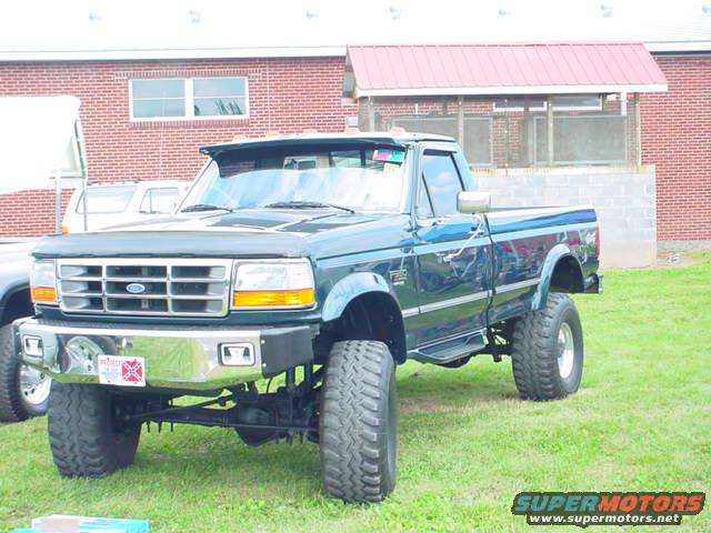 Dark green lifted pickup truck, front quarter view. License plate visible