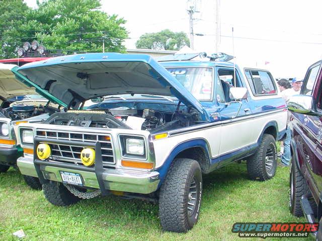 1979 Ford Bronco, blue and white, hood open, parked on grass next to another vehicle