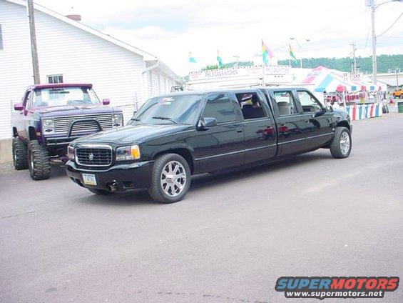 Black extended cab pickup truck limo parked next to a lifted purple pickup truck