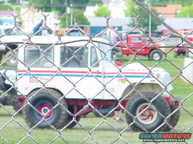 Side view of a white off-road vehicle with red and blue stripes and large tires