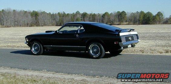 Black 1970 Ford Mustang Mach 1 with a rear spoiler on a paved road