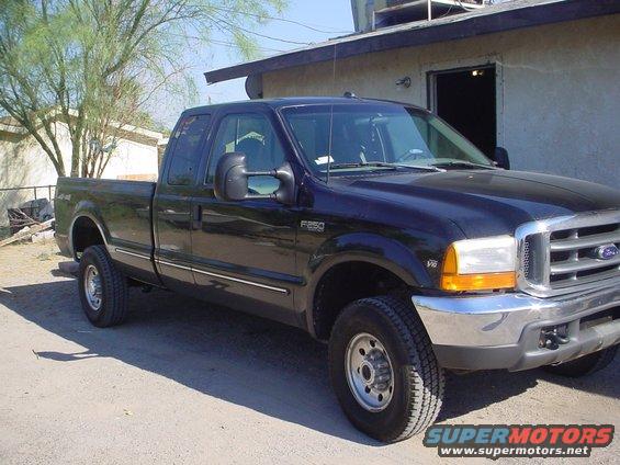 Black 1999 Ford F-250 Super Duty pickup truck parked outside a building