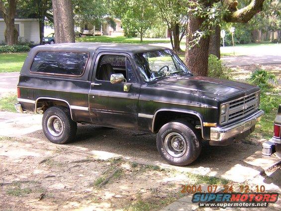 Black 1984 Chevrolet K5 Blazer parked on dirt lot. Front grille and side profile are visible