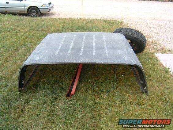 removed vehicle roof sitting on grass, spare tire nearby
