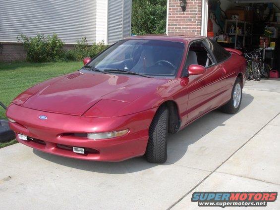 Red 1996 Ford Probe coupe parked on concrete driveway, front 3/4 view
