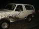 1989 Ford Bronco - This white Ford Bronco is heavily covered in mud, indicating off-road use.