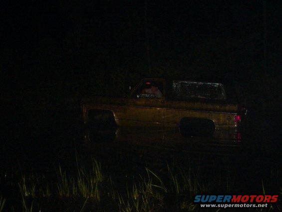 Yellow pickup truck stuck in water at night