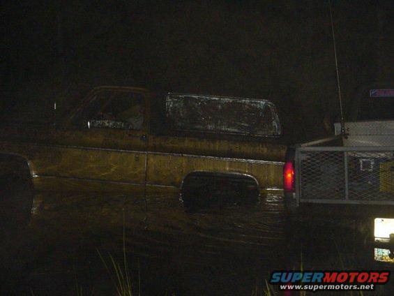 Muddy pickup truck with a trailer attached, seen at night