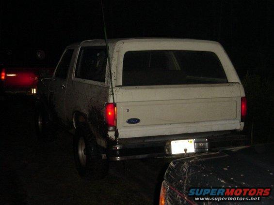 White SUV with mud splatters, rear view, parked at night