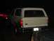 1989 Ford Bronco - A white SUV is parked at night, with another vehicle partially visible in the foreground.