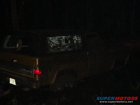SUV stuck in mud at night, rear view