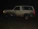 1989 Ford Bronco - Side view of a white Ford Bronco, heavily soiled with mud, seen in darkness.