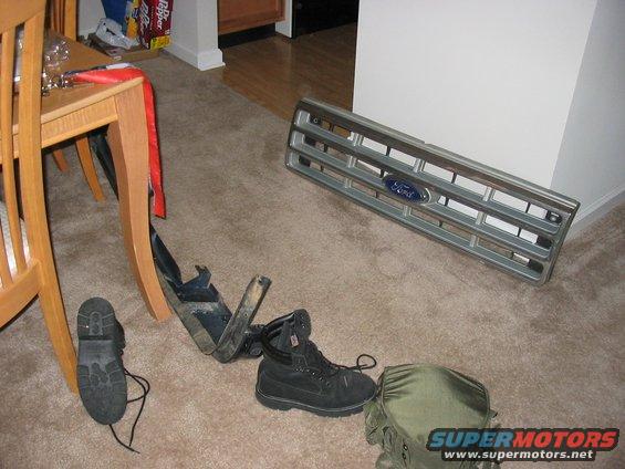 Ford grille and two pairs of boots on carpet
