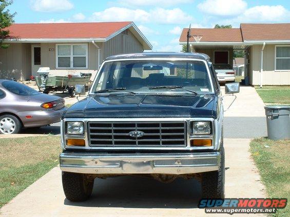 Front view of a dark-colored Ford pickup truck with a chrome grille and bumper