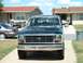 1982 Ford Bronco - A dark Ford pickup truck is parked in a driveway in front of a residential building.