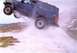 1990 Ford Bronco - SUV airborne during a jump over snowy terrain, creating a spray of snow.
