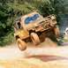 1990 Ford Bronco - This off-road vehicle is captured mid-air during an off-road event, kicking up dust.