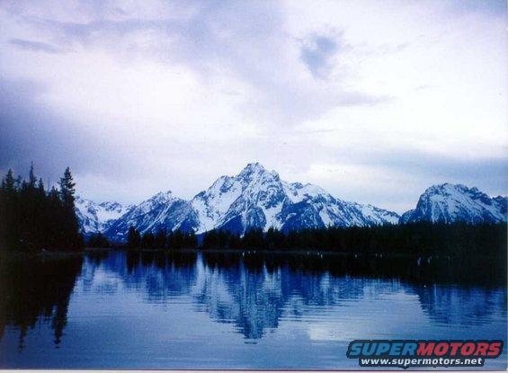 Mountain range reflected in a calm lake under a cloudy sky