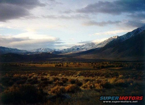 Mountain range under cloudy sky, with dry brush in the foreground