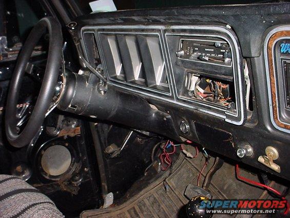 Dashboard of an old truck with exposed wires and a missing radio