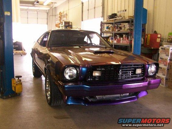 1978 Ford Mustang II with a custom paint job in purple and brown, seen from a 3/4 front angle in a garage