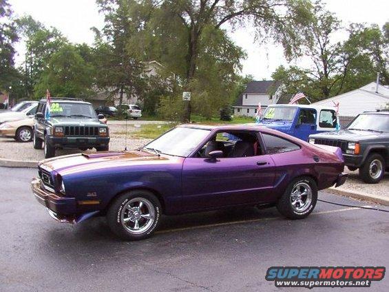 Purple coupe with custom paint, chrome wheels, and a hood scoop, parked outdoors