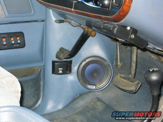 Interior shot of a vehicle's dashboard with a speaker, pedals, and gear shift