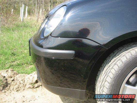 Front corner of a black car, showing headlight and tire. Supermotors.net logo visible