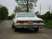 1979 Chevrolet Caprice - A white sedan is parked on a dirt road with trees and utility poles in the background.