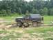 1988 Ford Bronco - A muddy Ford Bronco drives over logs on an off-road course.