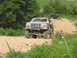 1988 Ford Bronco - This modified Ford Bronco is navigating a dirt path, with other vehicles visible in the distance.