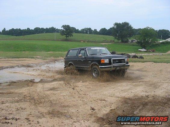 Black 1988 Ford Bronco driving through mud