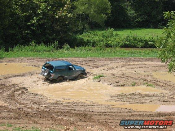 Teal SUV stuck in a mud pit, tires submerged