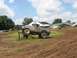 1988 Ford Bronco - A heavily modified off-road vehicle navigates an obstacle course on a sunny day.