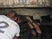 1988 Ford Bronco - Two individuals are inspecting the undercarriage of a heavily soiled vehicle, possibly for repairs or modifications.