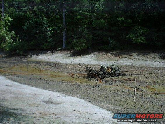 Off-road vehicle stuck in mud with trees in background
