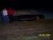 1994 Ford Bronco - Pickup truck overturned on the side of the road at night with onlookers.