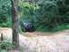 1988 Ford Bronco - Black Ford Bronco navigates a challenging dirt trail surrounded by dense forest foliage.
