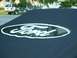 1990 Ford Bronco - A close-up of a Ford logo is shown, with a white SUV visible in the background.