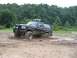 1988 Ford Bronco - This black Ford Bronco is navigating a challenging muddy terrain, kicking up water and dirt.