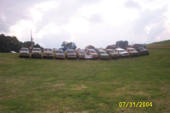 Line of trucks parked on a grassy field under a cloudy sky