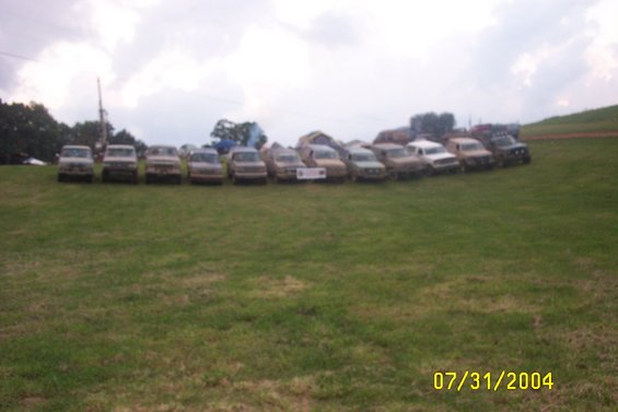Several pickup trucks parked in a grassy field on a cloudy day