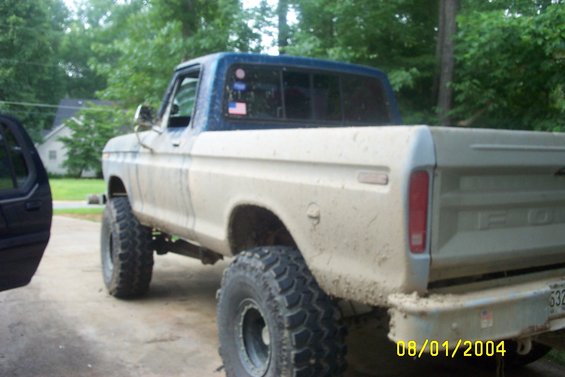 1979 Ford F-150 pickup truck, lifted with large tires, covered in mud. Rear view shows tailgate and bumper