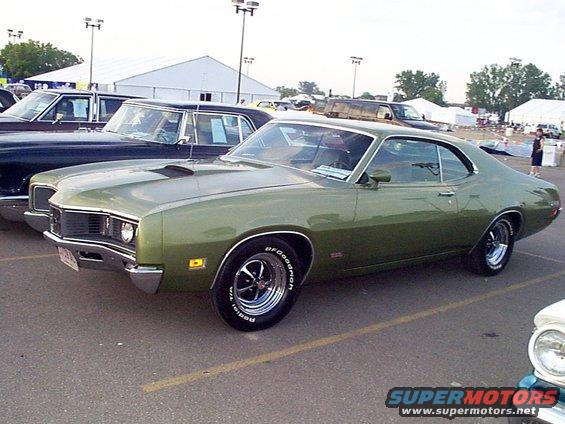 Green coupe with chrome wheels and hood scoop, parked in lot