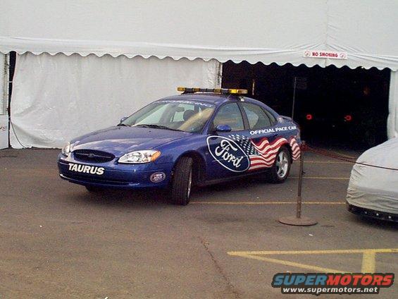 Blue Ford Taurus with American flag graphics and 'Official Pace Car' text. Has lights on roof