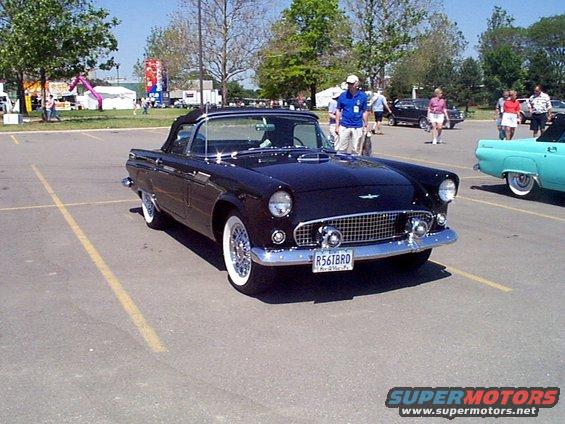 Black 1955 Ford Thunderbird convertible parked in a lot with a teal car to the right