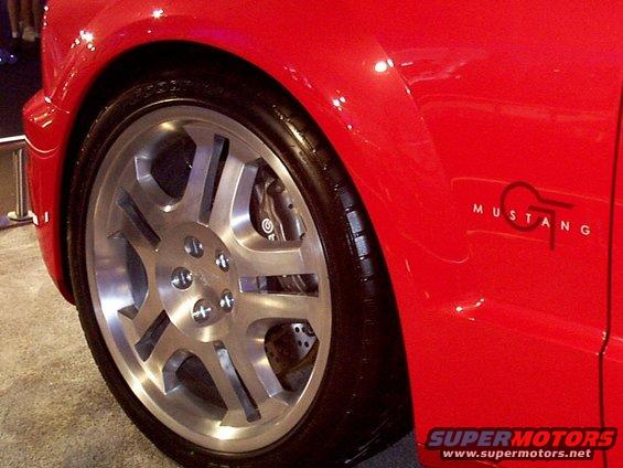 Close-up of a red car's front wheel and fender with a GT Mustang badge