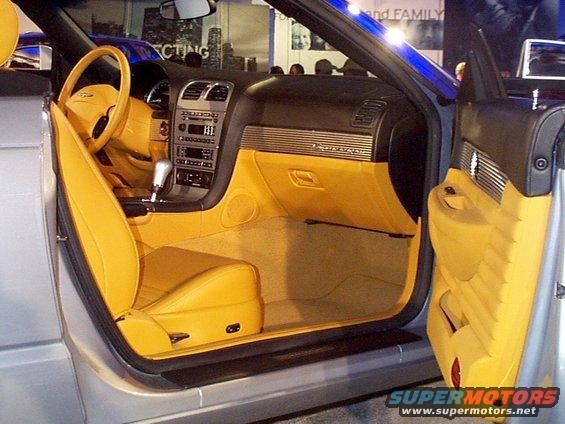 Car interior with yellow leather seats and dashboard, silver exterior, open driver's door